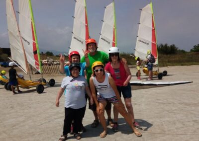 Petit groupe Loisirs Adaptés avec des chars à voile en fond