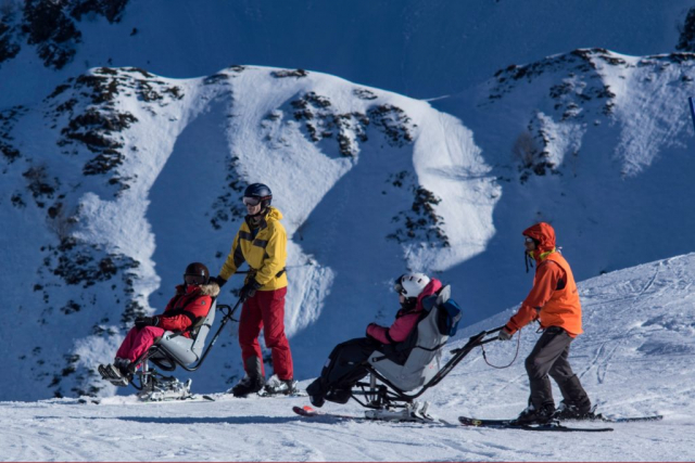 deux pilotes et deux personnes en fauteuil ski en montagne