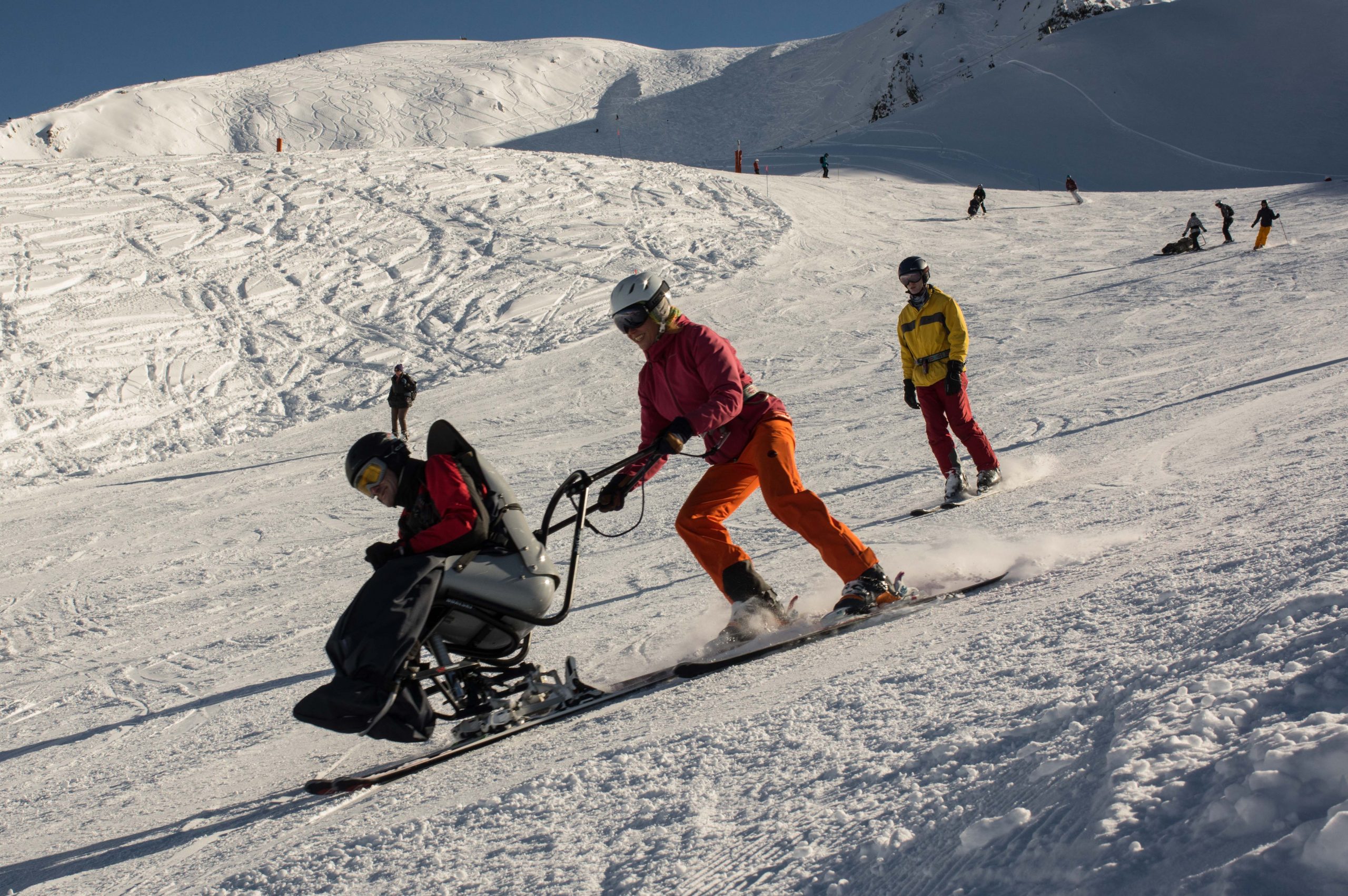 Pilote et skieur en fauteuil-ski sur une piste